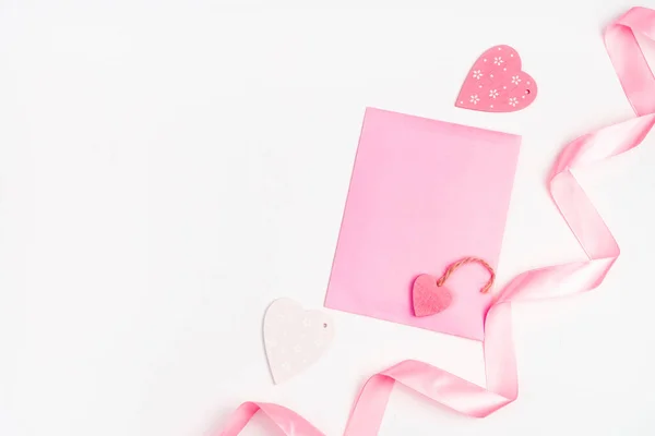 Corações, fita e envelope rosa em um fundo claro. — Fotografia de Stock