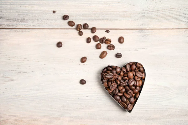 Coffee heart on a light background. A flying heart with a tail of scattered grains.