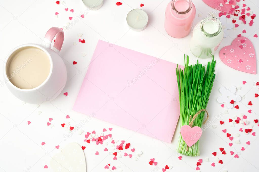 A Cup of coffee, a pink envelope and a decorative green bouquet on a romantic background.