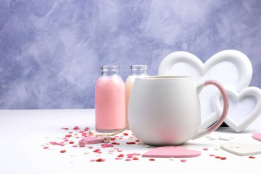 Yuvarlak Kupa, romantik bir arka planda bir içki çerçevesi ve beyaz ve mor arka planda bir şişe süt içeceği..