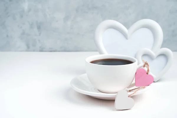 Romantic background with a Cup of coffee, a heart frame and hearts on a white-gray background. — Stock Photo, Image