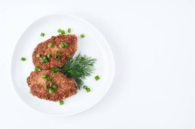 İki sulu pirzola yeşil soğan ve beyaz bir tabakta hafif bir zemin üzerine dereotu serpiştirilir..