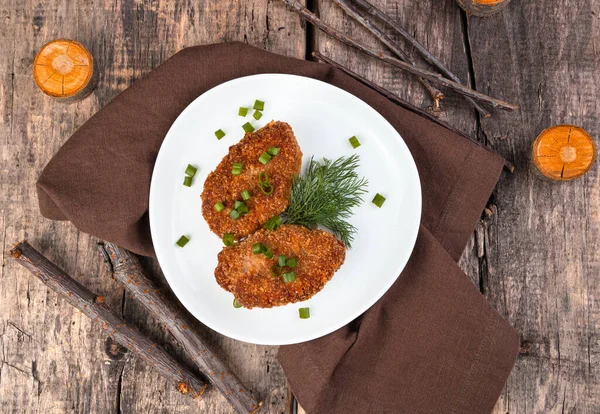 Turkey cutlets with herbs on a wooden background.