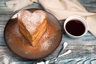 Kalp şeklinde waffle 'lar gri arka planda pudra şekeri ve kakao serpiştirilir..