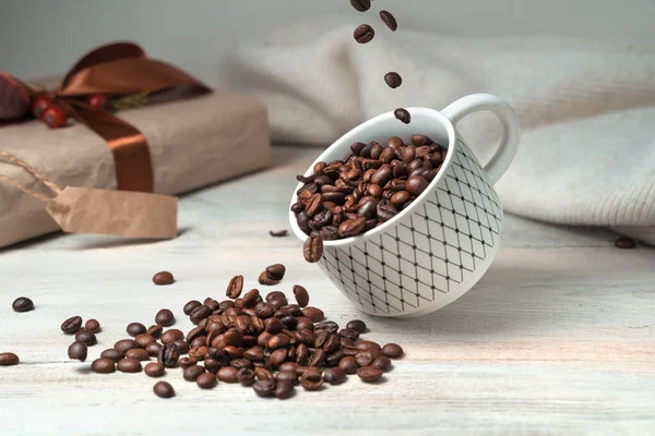 Verter granos de café en una taza voladora sobre un fondo festivo. —  Fotos de Stock