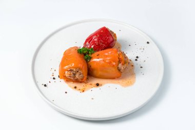 Beyaz tabakta etli üç kırmızı ve turuncu Bulgar biberi.