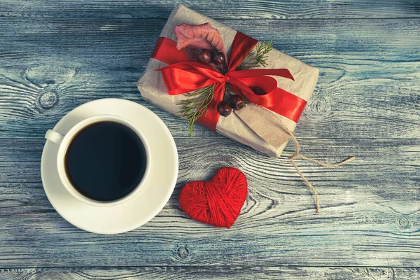 Festive composition with a gift, coffee and a heart on a gray-blue wooden background. — Stock Photo, Image
