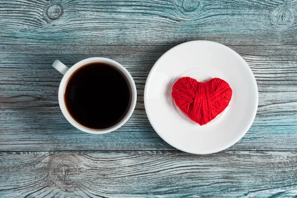 A red heart in a white saucer next to a Cup of coffee. — Stock Photo, Image