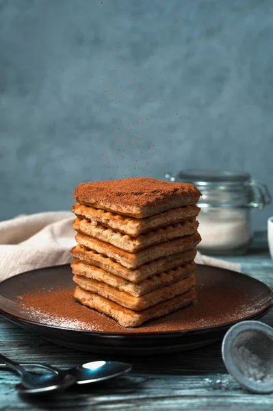 A stack of cocoa-dusted waffles on a wooden gray-blue background. — Stock Photo, Image