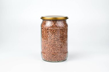 Beyaz arka planda şeffaf bir kavanozda karabuğday.