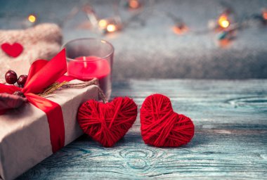 İki kırmızı kalp ve şenlik arka planında bir hediye kutusu..