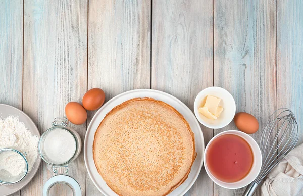 Eggs, flour, sugar, honey and pancakes on a light wooden background. — Stock Photo, Image