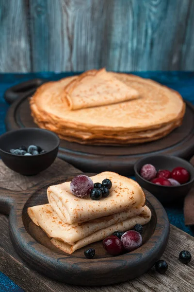 Sobremesa com panquecas e bagas congeladas em um fundo azul escuro. — Fotografia de Stock