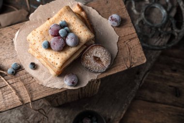 Donmuş böğürtlen ve pankekler ahşap üzerinde atmosferik bir arka planda.
