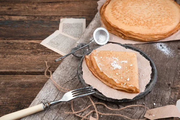 Gebratene Pfannkuchen mit Puderzucker auf altem Holzgrund. — Stockfoto