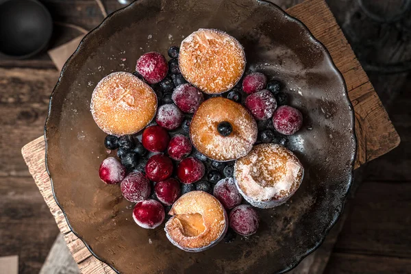 Замороженные вишни, горный ясень и сливы с морозом в прозрачной коричневой тарелке на деревянном фоне. — стоковое фото