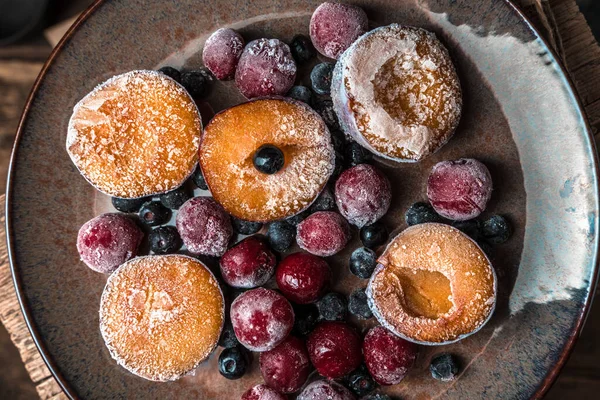 Замороженные ягоды, сливы и вишни в коричневой тарелке на деревянном фоне. — стоковое фото