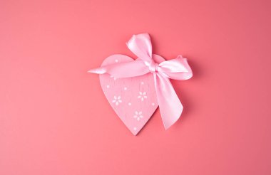 Pembe arka planda pembe bir kalp ve fiyonk.