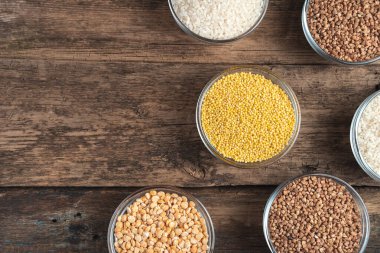 Tahta arka planda farklı mısır gevrekleri olan kaseler.