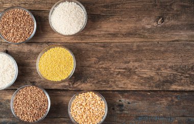 Tahta arka plandaki yuvarlak kaselerde farklı tipte tahıl gevrekleri. Üst görünüm, kopyalamak için boşluk.