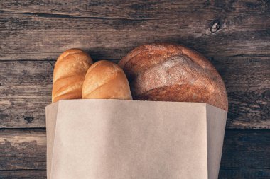 Tahta bir arka planda poşette taze, kabuklu ekmek. Üst görünüm, kopyalamak için boşluk.
