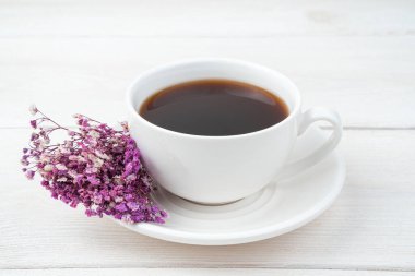 Seramik kahve fincanı ve beyaz arka planda bir buket çiçek. Yan görünüm, yakın plan.