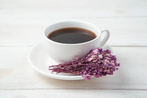 Flowers on a white coffee cup on a light background. Side view.