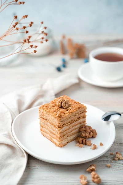 Sweet honey dessert with nuts on a soft light background. Side view, vertical orientation.