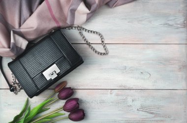 Hafif ahşap arka planda çanta, eşarp ve lalelerle şenlikli bir arka plan..