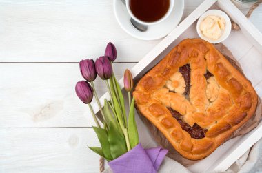 Meyveli turta ve arka planda bir buket lale. Kopyalamak için boşluk olan üst görünüm.