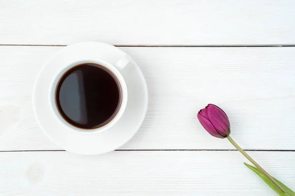 March 8, one tulip and a cup of coffee on a light wooden background. — Stock Photo, Image