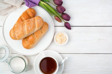 Hafif arka planda taze çörekleri, çayı ve laleleri olan şenlikli bir arka plan..