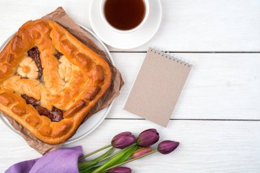 Elmalı turta, not defteri ve arka planda laleler. Üst görünüm, kopyalamak için boşluk.