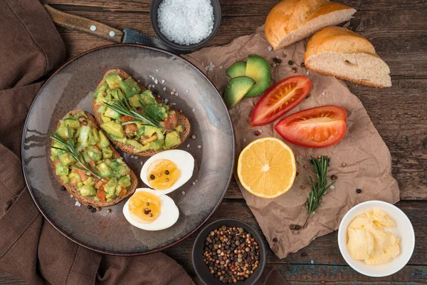 Вегетарианский обед с бутербродами с гуакамоле, вареными яйцами, помидорами и лимоном на деревянном фоне. — стоковое фото