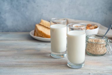 Taze süt, yulaf ezmesi ve gri arka planda ekmek. Kopyalama alanı olan yan görünüm.