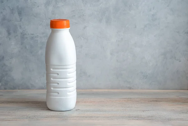 Botella de leche blanca con tapa naranja sobre fondo gris. — Foto de Stock