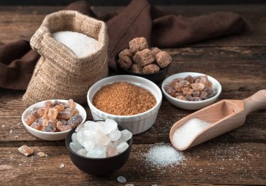 Tahta arka planda farklı eyaletlerde kamış ve beyaz şeker. Yan görünüm.