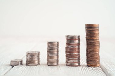 Bozuk para yığınları hafif bir arkaplanda yüksekliğe göre düzenlenir. Kopyalama alanı olan yan görünüm.