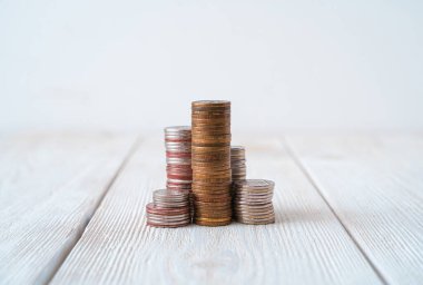 Hafif arka planda kuleler şeklinde yığılmış madeni paralar. Kopyalama alanı olan yan görünüm.