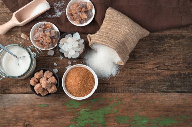 Tahta arka planda beyaz ve kamış şekeri farklı şekillerde..