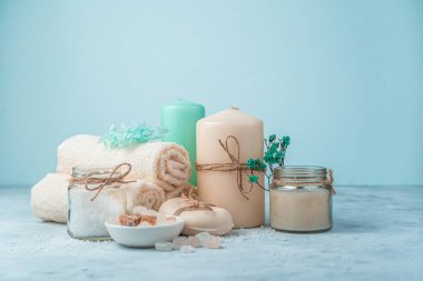 Açık mavi arka planda mumları olan spa seti. Kopyalama alanı olan yan görünüm.