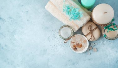 Yumuşak mavi arka planda bakım ürünleri olan spa seti. Yan görünüş, manzara.