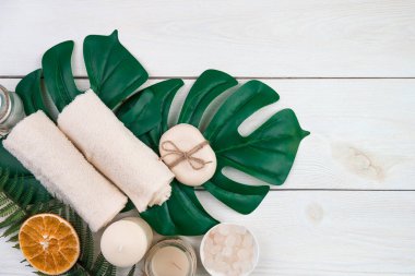 Beyaz ahşap arka planda canavar yaprakları üzerine kurulmuş bir spa..