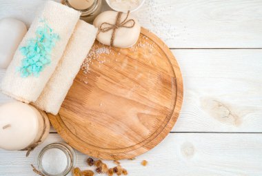 Beyaz ahşap arka planda bakım ürünleri ve cyan çiçekleriyle spa kompozisyonu.