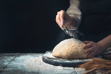Hamur, aşçılar tarafından serpilmiş. Koyu bir arka plan üzerine..