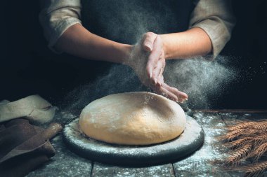 Aşçının elleri hamuru serpiyor ve un bulutu toz gibi uçuşuyor..