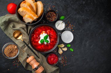 Siyah arka planda ekşi krema, ekmek ve baharatlı çorba. Üst görünüm, yatay.