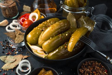 Salatalıklı siyah bir tabak ve baharatlı siyah bir arka planda doğranmış salatalıklı bir çatal..