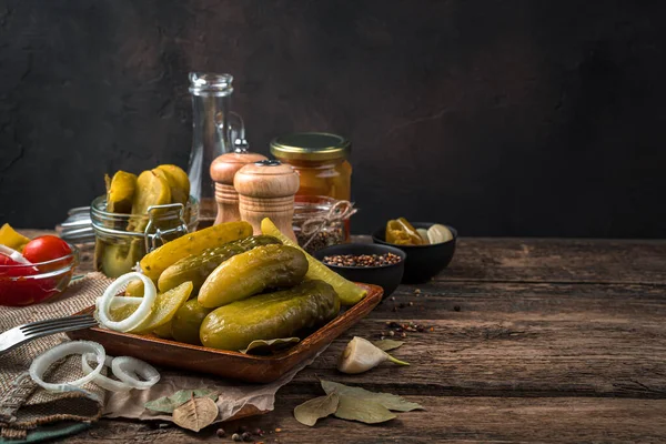 Pickled cucumbers and spices on a brown background.