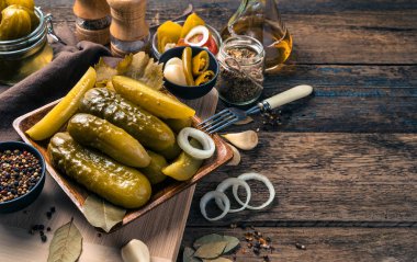 Kıtır turşu, soğan ve baharatlar doğrayıcı bir tahtanın üzerinde..